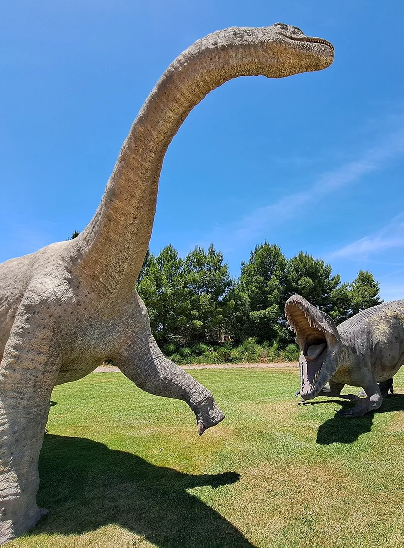 The foreground Aragosaurus model at Dinópolis presents an artistic sauropod reconstruction; the background predator is a separate model